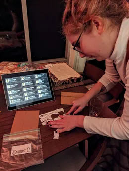 Person next to a tablet displaying the guest list app, with the person putting together a ripped check