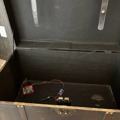 Antique steamer trunk treasure chest open, with an electromagnet visible near the latch. A Raspberry Pi computer is wired into the electromagnet